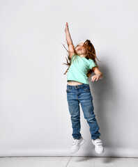 Little happy fitness girl child jumping stretching arm up studio shot