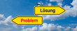 © fotogestoeber - signpost with two arrow-shaped signs with the German words for PROBLEM and SOLUTION in opposite direction in front of a cloudy sky