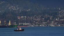 Tugboat Sailing In Vancouver Harbour For Its Next Drag Command With A Green Multi Purpose Vessel In The Background. Wide Steady Shot