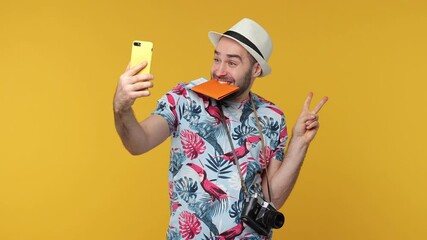 Wall Mural - Funny traveler tourist man in hat isolated on yellow background. Passenger travel on weekends. Air flight journey concept. Doing selfie shot on mobile phone kiss passport tickets showing victory sign