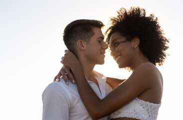 multiracial couple with african american young woman and caucasian man hugging outdoor in a warm sum