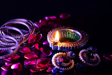 Flame Emitting From Blue Colorful Earthen Lamp Diya Surrounded With Jewellery  Ornaments And Rose Petals Floral Decoration. Deepawali Or Deepavali Brings In Prosperity In Life Concept