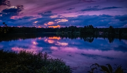 Wall Mural - Panoramic view of dramatic sunset over Midwestern lake; colorful clouds reflect in water