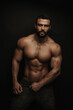 Fitness handsome and shirtless man standing on black background