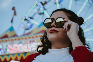 Wall Mural - Mujer latina con gafas de sol en el atardecer de un parque de diversiones