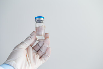 Doctor or scientist holding ampoule liquid vaccines with medication in the laboratory. Vaccination and immunization. Close up.