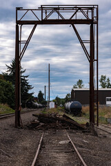 Old railroad track with wooden, arch structure against a blue sky with puffy, white clouds