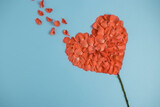 Fototapeta Tulipany - Flower in shape of a heart made of rose petals on light blue background. Love concept. Flat lay