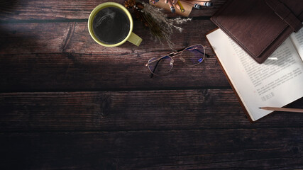 Top view of hipster vintage workspace with notebooks, pen, glasses and a cup of coffee on wooden table. Copy space for advertise text.