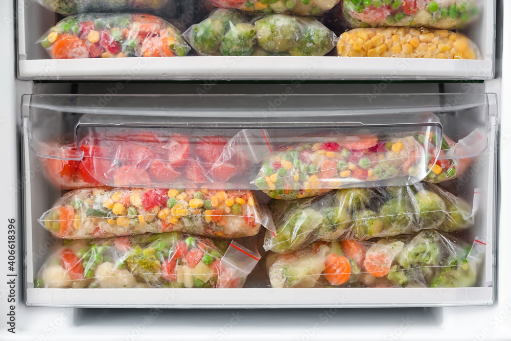 Plastic bags with frozen vegetables in refrigerator