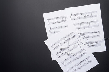 Wall Mural - Music sheets and earphones on dark background