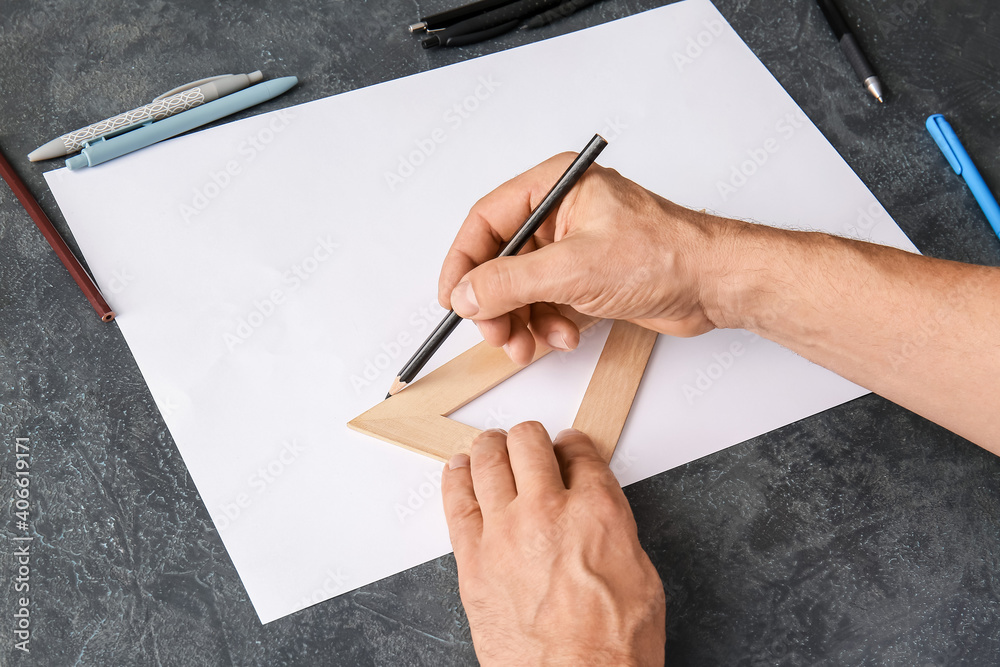 Male hands with blank paper sheet, pen and ruler on dark background