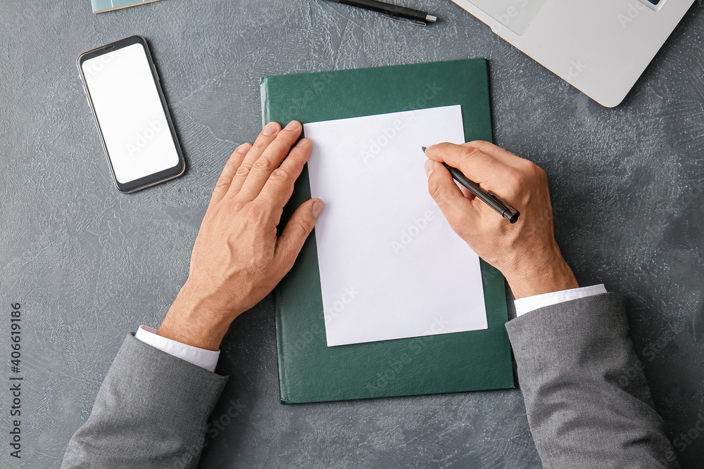 Male hands with blank paper sheet and mobile phone on dark background