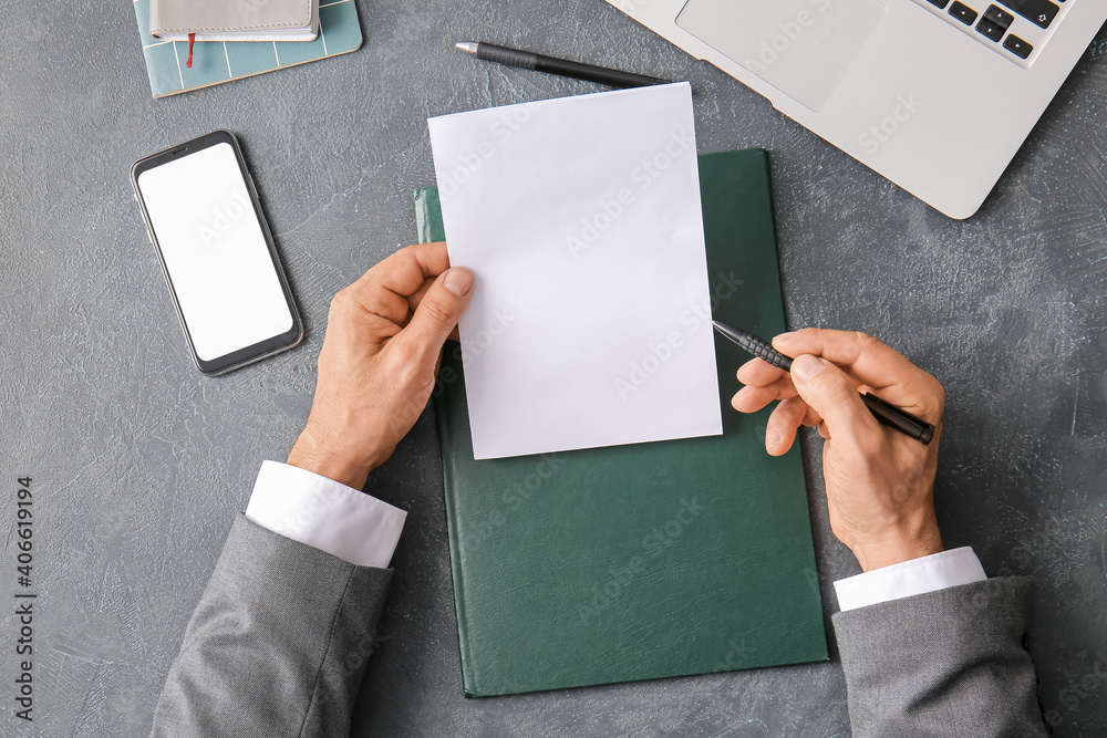 Male hands with blank paper sheet and mobile phone on dark background