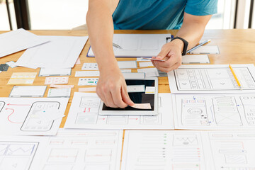 Graphic designers work together with UX UI designer planning application template layout framework for mobile phone computer mobile