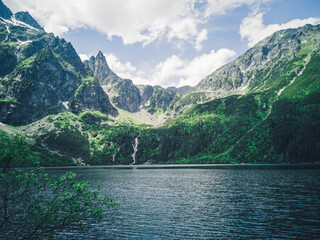 Beautiful alpine lake in the mountains, natural background, summer landscape with blue cloudy sky and reflection in crystal clear water, Morske Oko, Tatra Mountains, Zakopane, Poland