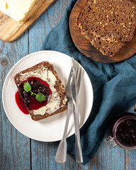 Bread with butter and blackcurrant jam. Rye bread sandwich with sunflower seeds with butter and jam. Breakfast