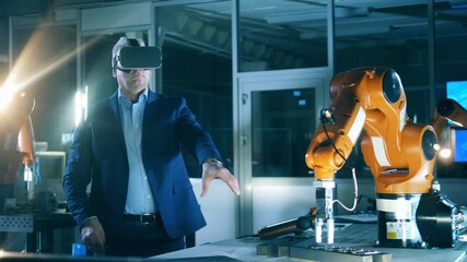 Wall Mural - male science worker is using vr-glasses to operate modern industrial robot
