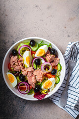 Wall Mural - Tuna salad with egg, olives and vegetables in white bowl, dark background. Diet food concept.