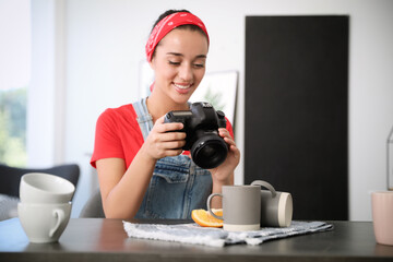 Poster - Young photographer taking picture of cups at table indoors, focus on camera