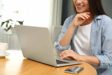 Poster - Young woman using laptop for search at wooden table in room, closeup