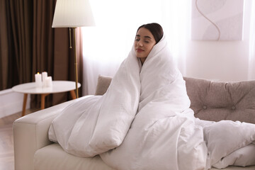 Canvas Print - Woman wrapped in blanket resting on sofa