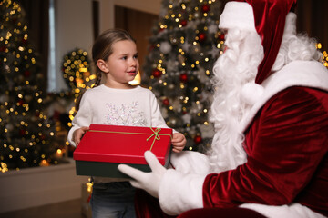 Wall Mural - Santa Claus giving present to little girl in room decorated for Christmas