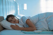© New Africa - Young woman sleeping on electric heating pad in bed at night