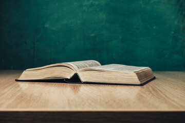 Aufkleber - Open holy bible on a  wooden table. Beautiful green wall background.