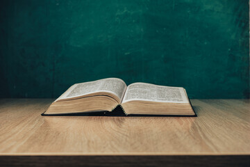 Aufkleber - Open holy bible on a  wooden table. Beautiful green wall background.