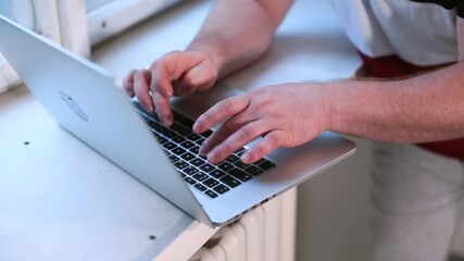 Poster - Male hands use laptop keyboard near the dormitory window. He prints fingers a text document in a computer application. Camera movement.
