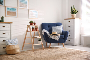 Poster - Stylish living room interior with wooden ladder and comfortable armchair