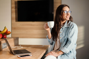 Attractive smiling young smart woman working on laptop