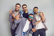 © Studio Romantic - Happy best friends having fun while hanging out together. Group of 4 young men in sunglasses smiling, looking at camera and posing for funny photo in studio with light gray background