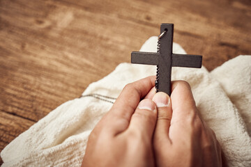 Concept of Christian. close up of hand praying holding a Jesus Christ black cross on the old wooden table background with copy space                                                                 