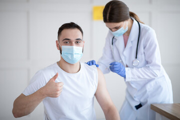 Poster - Young guy showing thumbs up during coronavirus vaccination at clinic, promoting covid-19 immunization