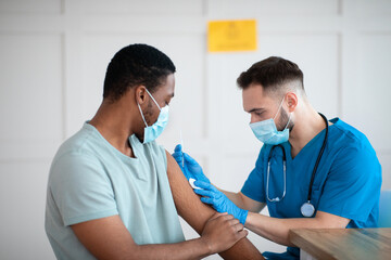 Poster - African American man in face mask receiving coronavirus immunization, taking shot of covid-19 vaccine at medical office