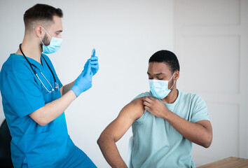 Poster - Covid-19 vaccination program. Black male patient getting coronavirus vaccine shot on visit to physician at health centre