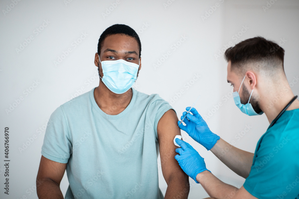 Immunization and health care system. Black male patient visiting doctor, receiving covid-19 vaccine injection at clinic - obrazy, fototapety, plakaty 
