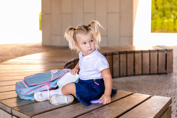 cute smiling little schoolgirl holding a hamburger and orange juice outdoor - back to school