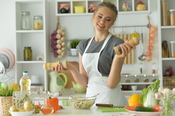 Beautiful young woman making  salad at home