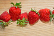 A row of red ripe strawberries on a wooden board.