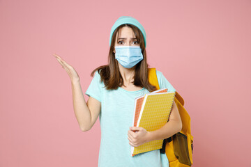 Wall Mural - Shocked young woman student in t-shirt hat backpack face mask to safe from coronavirus virus covid-19 spreading hands isolated on pink background. Education in high school university college concept.