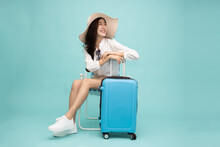 Asian Happy Woman Sitting On Chair With Suitcase Isolated On Green Background, Tourist Girl Having Cheerful Holiday Trip Concept