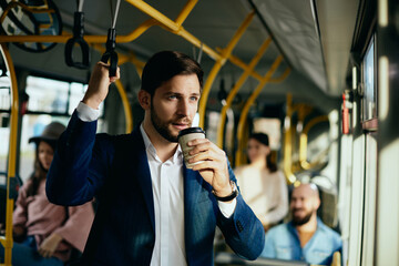 Wall Mural - Male entrepreneur having takeaway coffee while commuting to work by bus.