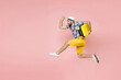 Full length side view of cheerful traveler tourist man in summer clothes hat jumping running hold suitcase isolated on pink background. Passenger traveling on weekend. Air flight journey concept.