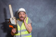 © Sergei - A European man with a chainsaw. A worker with a chainsaw is surprised and screams. A bright emotion of surprise.