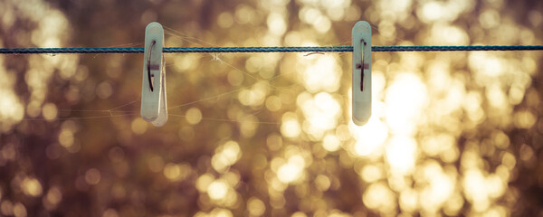 Two clothespins on a clothesline. Background Colorful autumn time in the forest, the sun shines through the foliage.