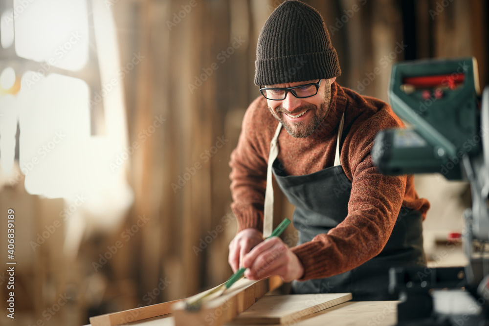 brutal male carpenter working in  workshop - obrazy, fototapety, plakaty 