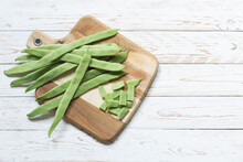 Green Beans On A Cutting Board And On A Rustic White Wood Background. Copy For Space And Text